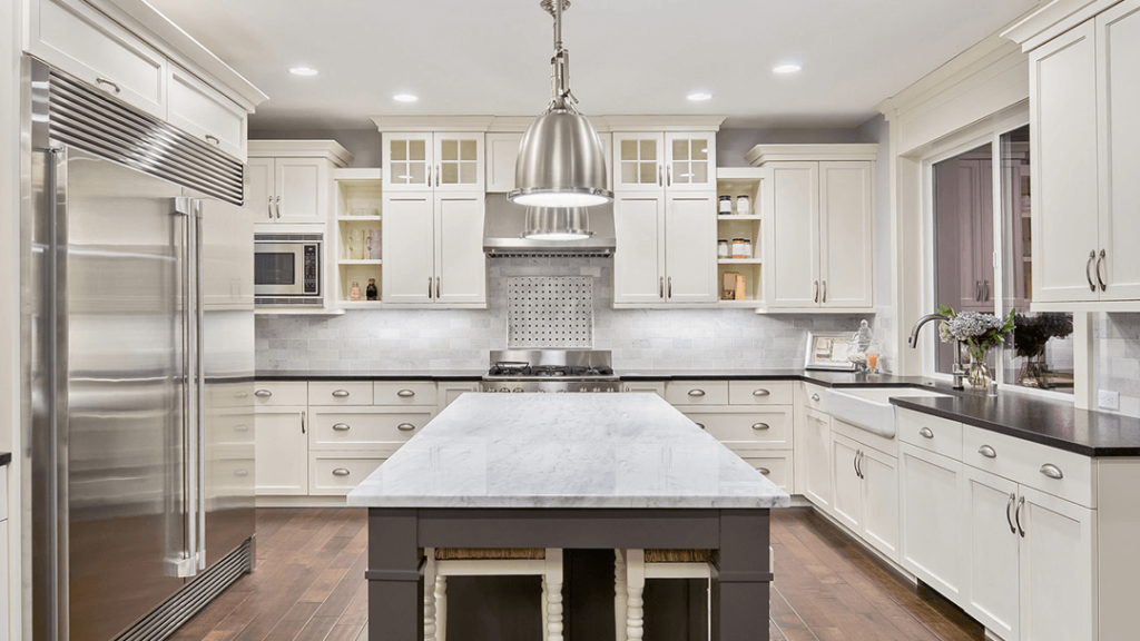 A kitchen with white cabinets and a large island.